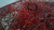 Close view of crimson field, teal leaf motifs and ivory corner spandrel under natural indoor light