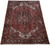Angled view of hand-knotted wool Heriz rug showing dark navy border and ivory corner spandrels