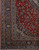 Corner detail showing navy main border, light blue guard bands and red floral spandrel