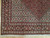 Corner detail showing cream Herati field, black palmette border, salmon guard stripes and clean ivory fringe