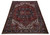 Rust red and indigo Heriz rug shown at an angle with ivory spandrels and geometric layout