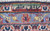 Woven signature cartouche in the top border above light blue guard stripe and ivory fringe