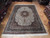 Hand-knotted 8x12 Jaipur wool rug displayed on parquet floor in the warehouse showroom