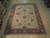8'10" x 11'10" hand-knotted Indian Chobi rug laid flat on light wood warehouse showroom floor