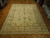 Cream and sage vegetable dyed wool rug displayed on parquet floor in bright showroom
