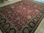 Angled view of burgundy red field with sage green palmettes and deep black floral border