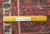 Ruler on pile showing hand-knotted wool weave, green and ivory border motifs, 8 inch scale