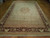 Angled view showing ivory field, camel end panel, zigzag band and deep burgundy main border