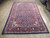 6'10" x 10'10" Persian rug in navy and rose red photographed on showroom hardwood floor