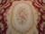 Close-up of the ivory oval medallion with pink rose bouquet framed by delicate laurel leaf wreath