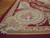Corner detail of flat weave wool rug showing tortilla brown border, pink roses and ivory cartouche