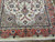 End view showing taupe spandrel, navy rosettes and pink blossoms against the cream Tabriz field