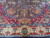 Detail of scalloped crimson spandrel meeting ivory main border with blue and red guard stripes