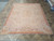 Angled showroom photograph of the 8' x 10' Aubusson rug highlighting pastel scrollwork and corner florals