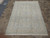 Light blue and cream Persian area rug laid out for living room scale reference on tile
