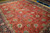 Angled view of large red and navy Tabriz carpet showing palmette repeat and ivory guard stripes