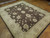 Angled view of large brown and beige Peshawar wool rug in a showroom