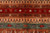 Close-up of brick red stripe with cube motifs, camel and deer figures on rust wool