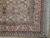 Corner detail with burgundy main border, black guard stripes, ivory vine scroll and clean cotton fringe