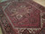 Angled view showing olive and rust medallion field, ivory cornerpieces and dense hand-knotted wool pile