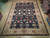 9'11" x 14'1" hand-knotted Pakistani rug laid flat on warehouse floor, navy field, ivory border