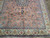 Angled view of coral orange field covered in blue floral vinework beside wide ivory palmette border