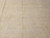 Macro of the low quarter inch wool pile revealing faint floral motifs in buttercream tones