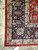 Corner detail showing ivory guard border, navy palmettes and cotton fringe on hand-knotted wool pile