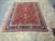 8'2" x 10'4" Oriental rug photographed in full on warehouse tile floor showing red and navy palette