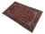 4x7 Kashan Persian rug photographed at an angle, crimson field inside deep indigo main border