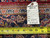 Back tag reading size 4'4 x 7 beside tape measure over indigo floral border weave