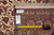 Back of the rug with dealer tag reading size 6.8 x 10.4 beside measuring tape
