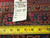 Back of rug with inventory tag reading 8258 and tape measure across the cotton foundation weave