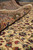 Rolled edge close-up showing dense wool pile, olive border and cream field with wine sprays