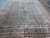 Full view of 11'8" x 14'9" navy and rust Herati rug on tile floor