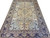 Hand-knotted Persian rug showing pale blue corner spandrels, hunting figures and deep navy floral border