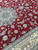Silk outlined palmettes and paisley vines curling across the crimson field beside the ivory main border
