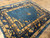 7x9 antique Chinese Peking wool rug viewed at an angle, gold urns and books on blue field
