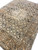 Angled floor view of antique Tabriz rug with navy vine scrollwork and wide camel outer border