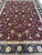 Close look at the all-over vine scroll, palmettes and rosettes covering the burgundy wool field