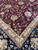 Border junction where burgundy field meets gold guard stripe and black main border floral vine