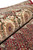 Rolled edge close-up showing silk sheen in the ivory border rosettes above the red herati field