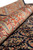 Rolled edge close-up showing rust border paisleys, green accents and soft natural wool pile