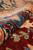 Rolled pile close-up showing plush natural wool, deep burgundy ground and indigo border detail
