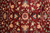 Field close-up of ivory palmettes, coral rosettes and navy accents on wine red wool ground