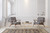 Charcoal and gold area rug anchoring a bright living room with grey mid-century chairs and brass table