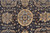 Field close-up showing gold and pale blue rosette medallion surrounded by scrolling vines on charcoal ground
