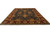 Angled floor view showing hand-knotted wool rug with deep navy field and wide burgundy floral border