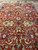 Close view of red field with ivory vinework, green palmettes and small navy diamond motif
