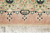 Woven signature cartouche in the green border end panel above the ivory cotton fringe